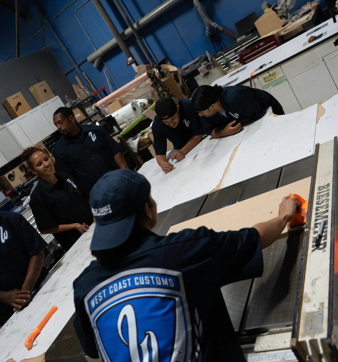 Academy students in WCC uniforms working around a CNC cutting table