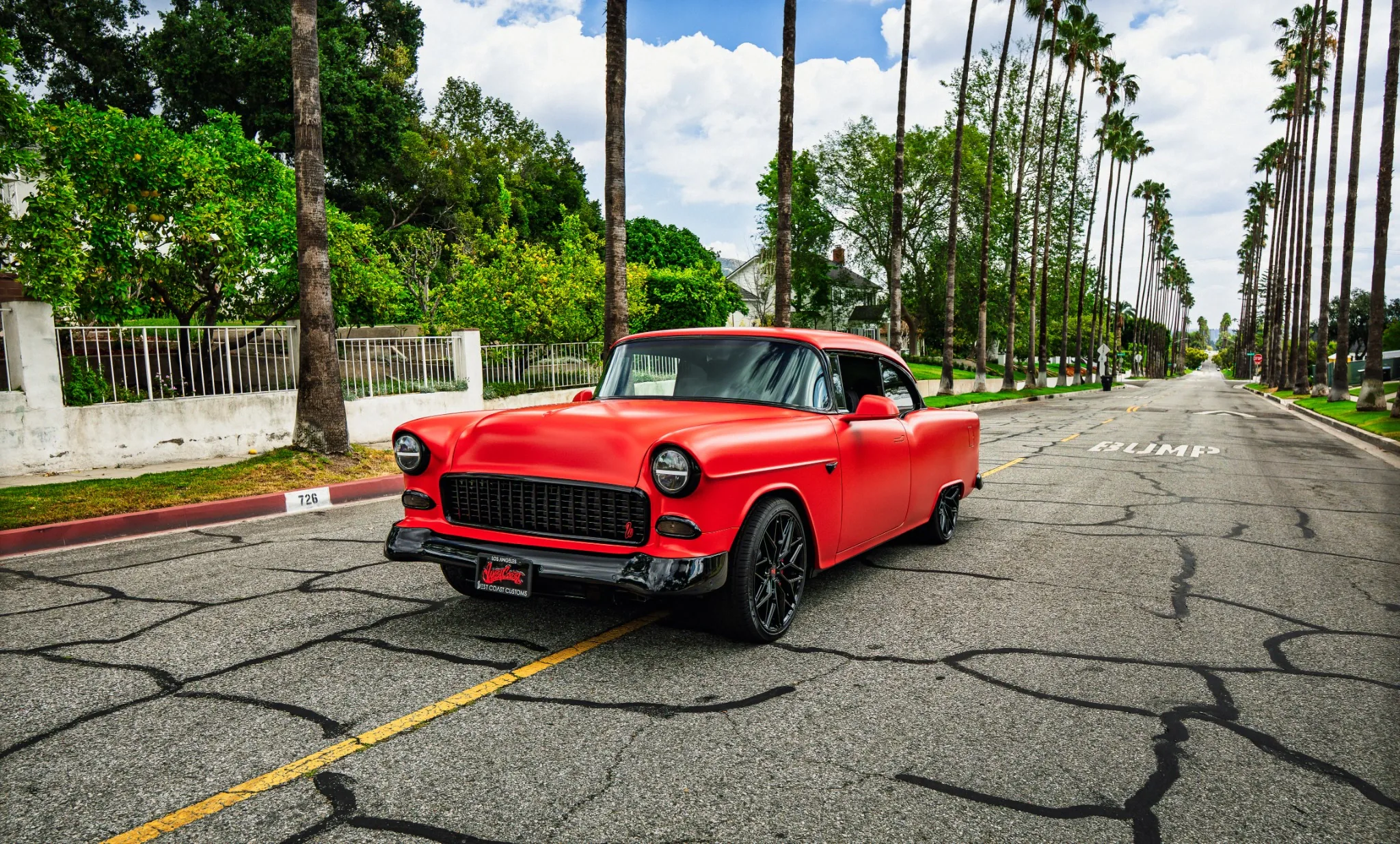 Red West Coast Customs build on a palm-lined Southern California street